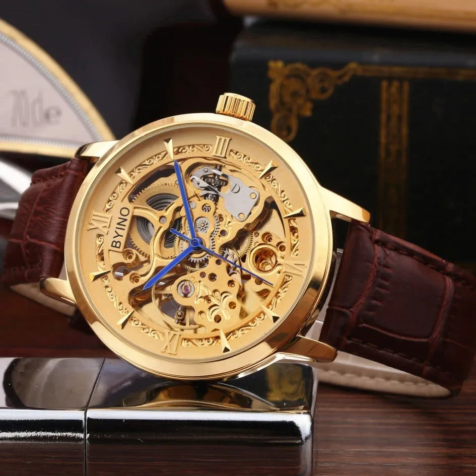 Men's automatic mechanical watch with skeleton dial, leather strap, and gold-tone case on a neutral background