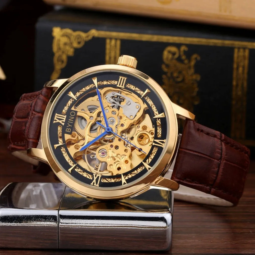 Men's automatic mechanical watch with skeleton dial, leather strap, and gold-tone case on a neutral background