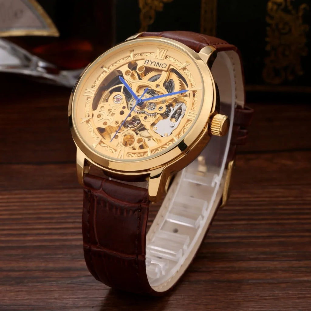 Men's automatic mechanical watch with skeleton dial, leather strap, and gold-tone case on a neutral background