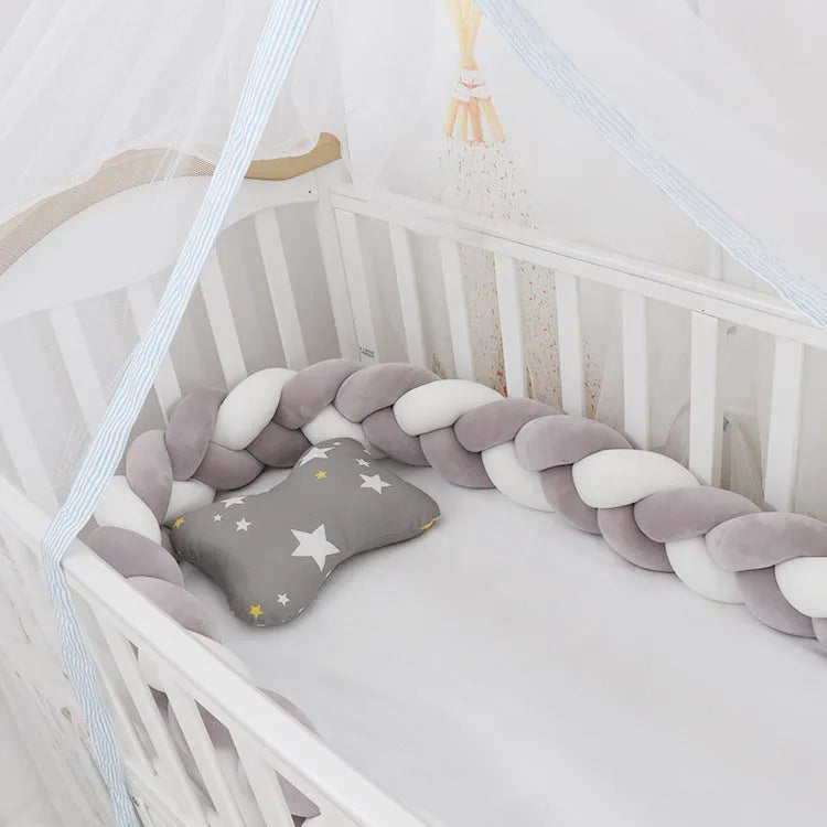 Braided knot pillow cushion bumper for infant crib in spandex velvet, shown in a light colour.