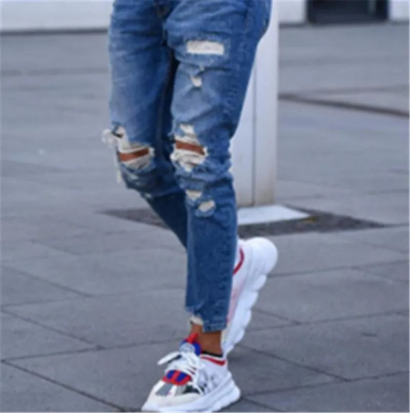 Deep blue men's jeans with distressed holes on the knees, laid flat.