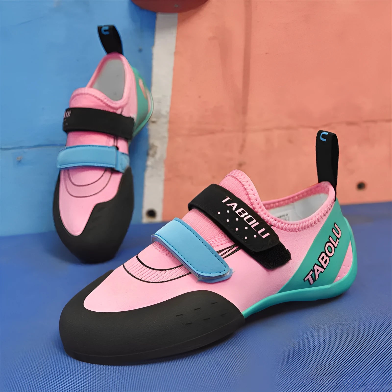 Black and red beginner rock climbing shoes with velcro strap and rubber sole on a climbing hold.