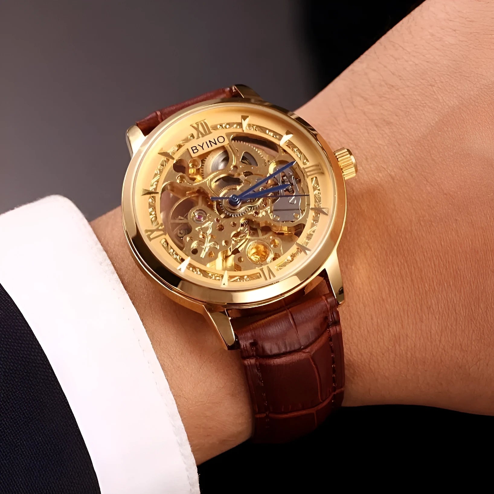 Men's automatic mechanical watch with skeleton dial, leather strap, and gold-tone case on a neutral background