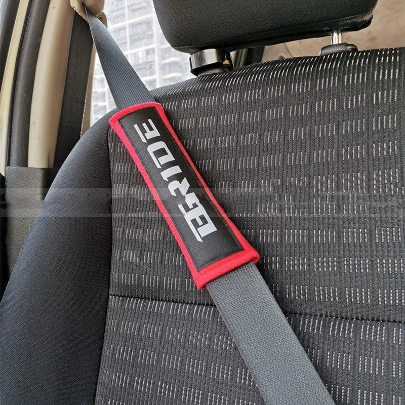 Pair of black car seatbelt shoulder pads showing embroidery detail and thickness