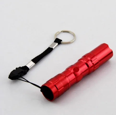 Black aluminium mini LED flashlight on a table showing its 9.5 cm length and 2 cm diameter.