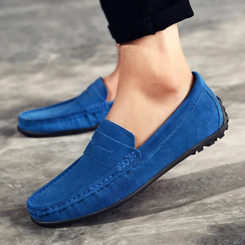 Men's suede leather Gommino loafers in black on a flat rubber sole, showing round toe and sewing line detail.