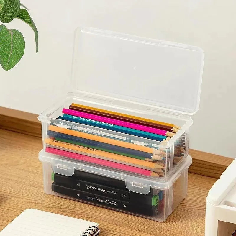 Clear plastic storage box for pencils, colouring leads, and children's crayons on a desk.