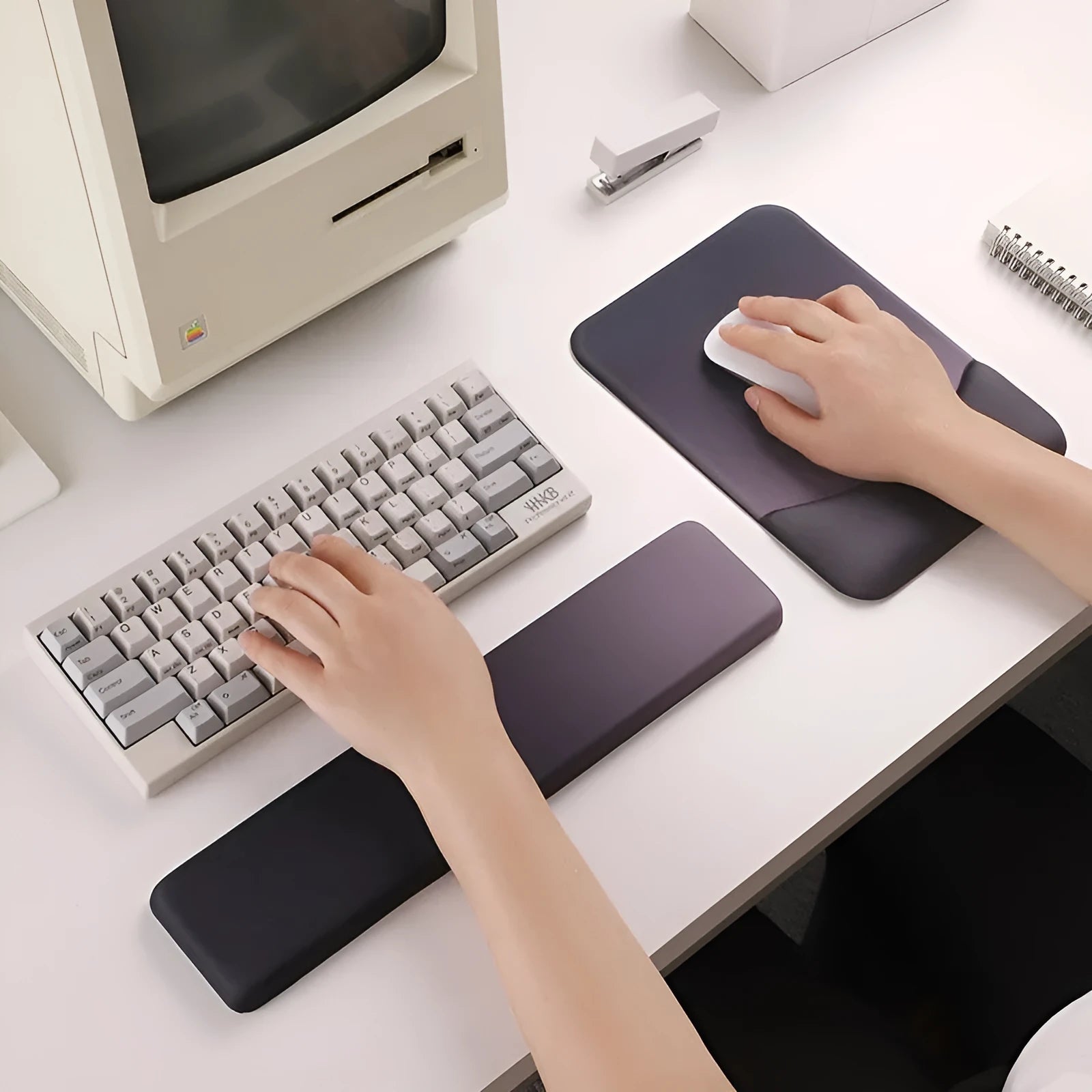 Square black silica gel mouse pad with raised keyboard support area and integrated wrist rest on a wooden desk.