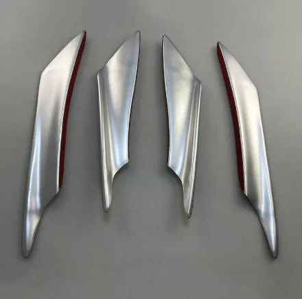 Set of four carbon fibre pattern bumper blade spoilers for car modification on a black background.