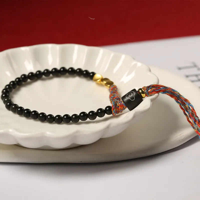Hand-woven obsidian carrying strap bracelet showing textured weave and 4mm width