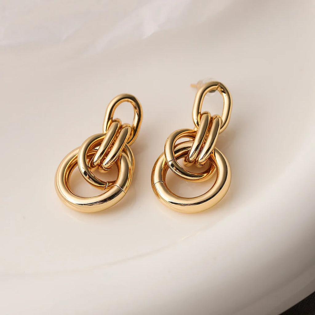 Geometric gold drop earrings with an irregular shape on a copper base.