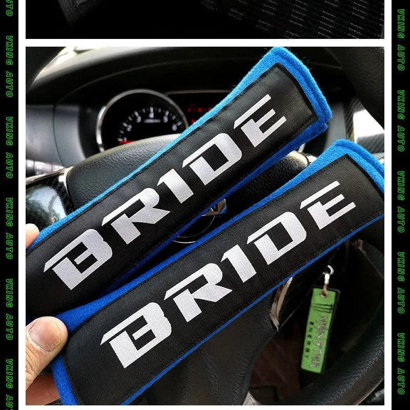 Pair of black car seatbelt shoulder pads showing embroidery detail and thickness