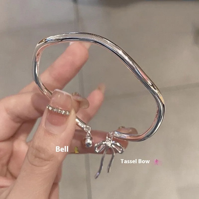 Silver adjustable bracelet with bow detail and bell opening clasp on wrist