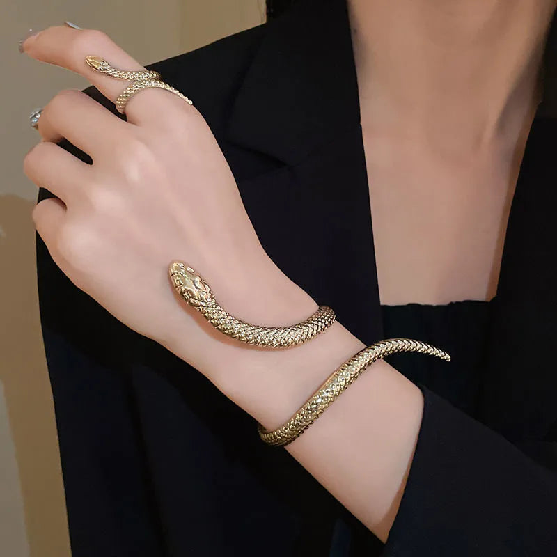 Gold tone snake-inspired bracelet and ring set with exaggerated twisted winding design on white background