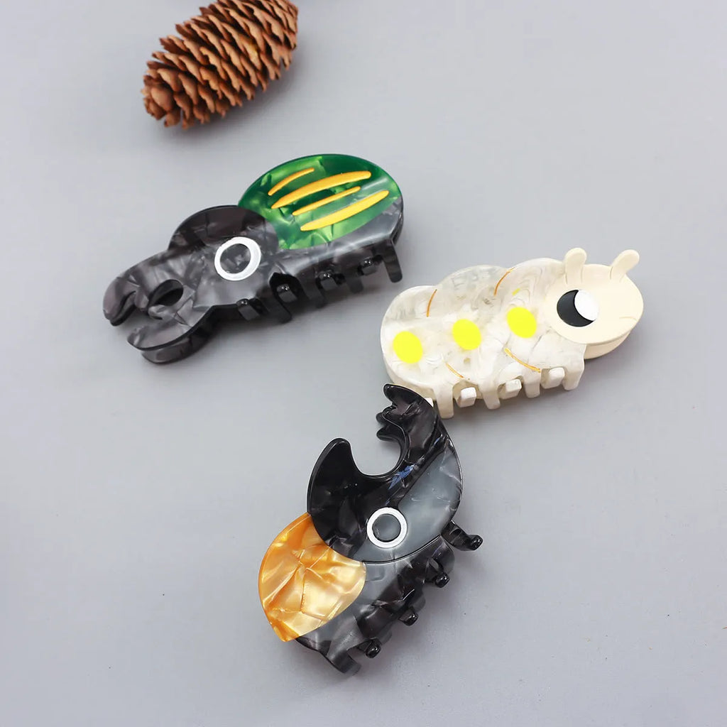 Handmade cellulose acetate beetle grip showing green beetle, orange beetle, and white caterpillar colour variants