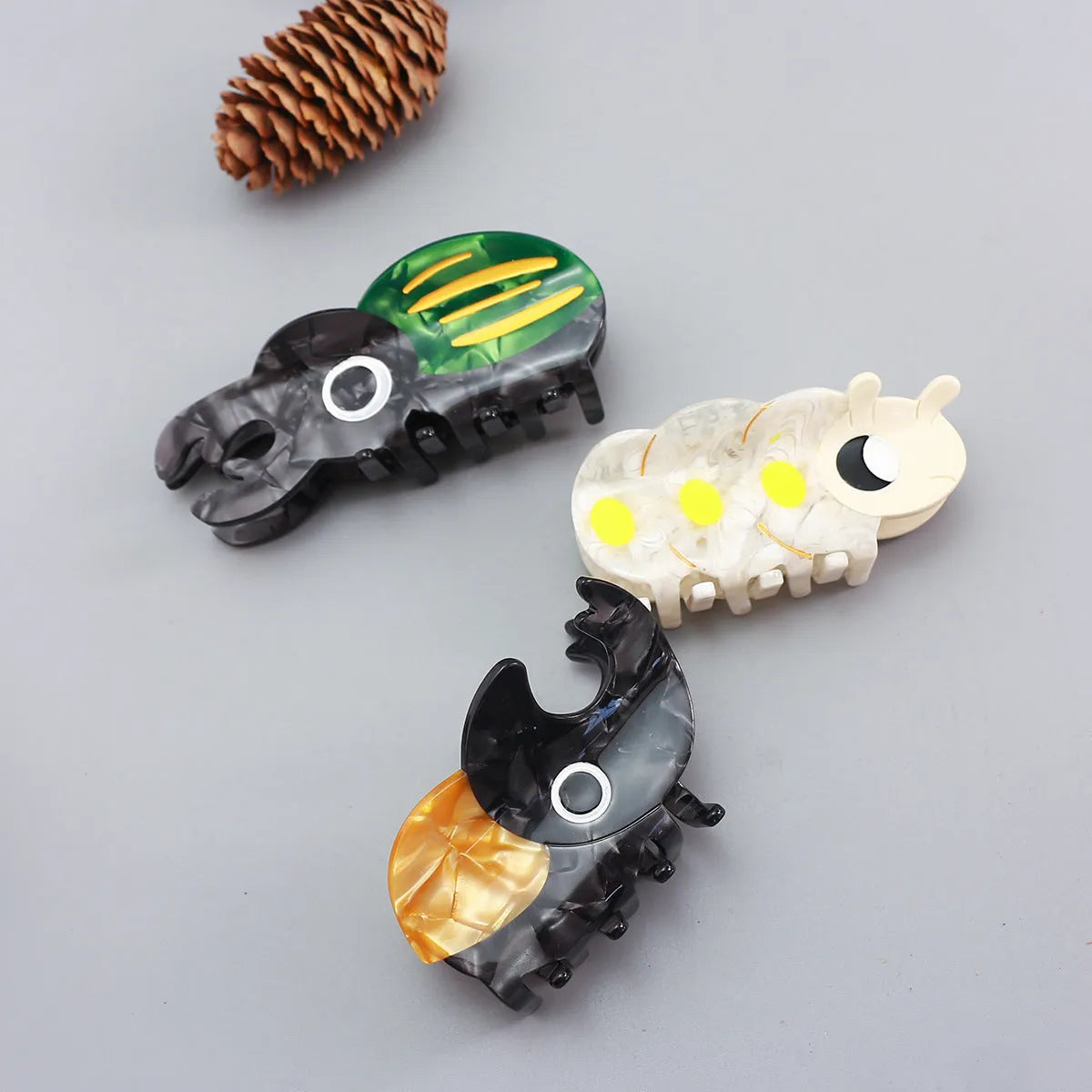 Handmade cellulose acetate beetle grip showing green beetle, orange beetle, and white caterpillar colour variants