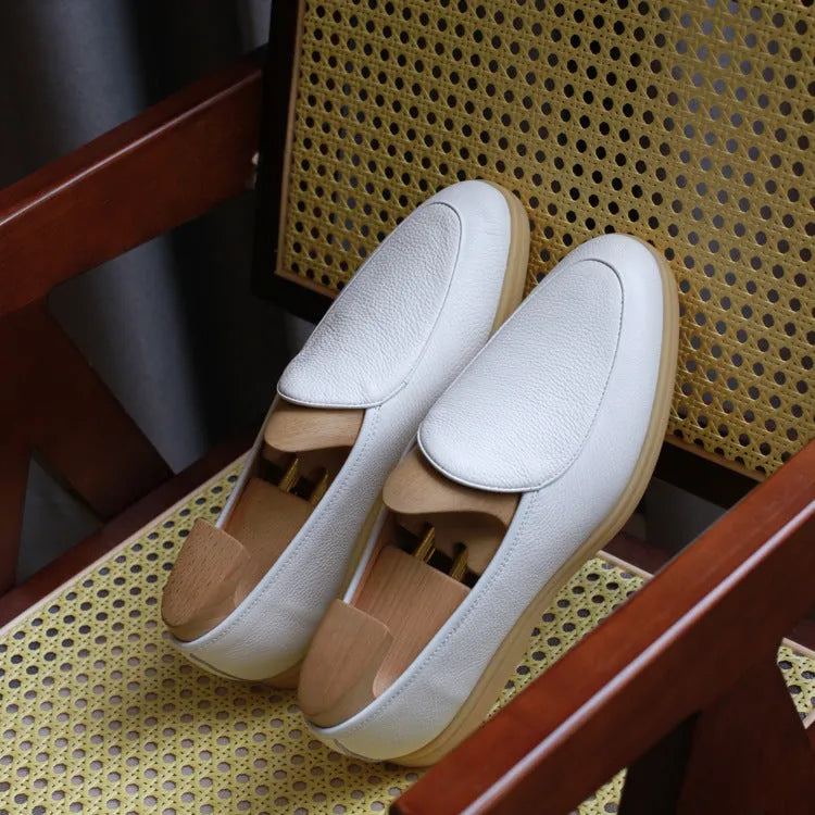 Men's brown genuine leather handmade loafers on a white background, showing the low-cut slip-on design and textured sole.
