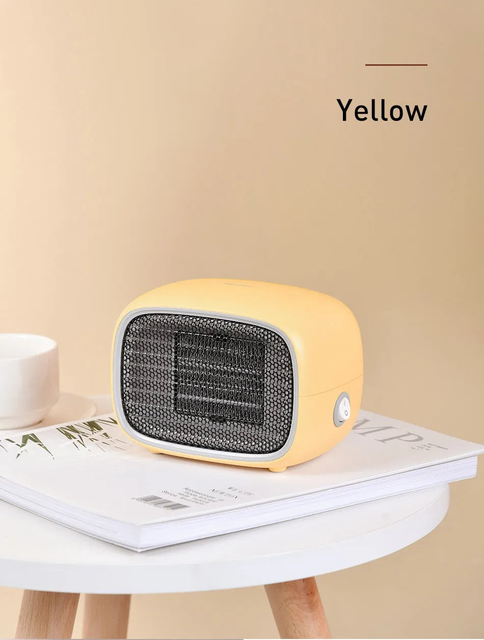 Compact green mini ceramic desk heater with metal mesh front grille, shown next to a pen for scale.