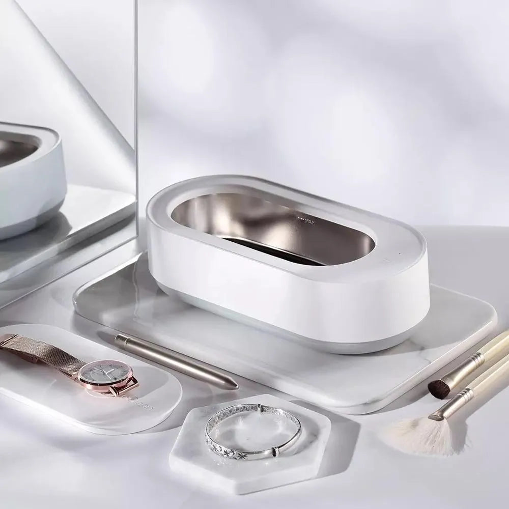White portable ultrasonic cleaner with stainless steel tank and a single control button.