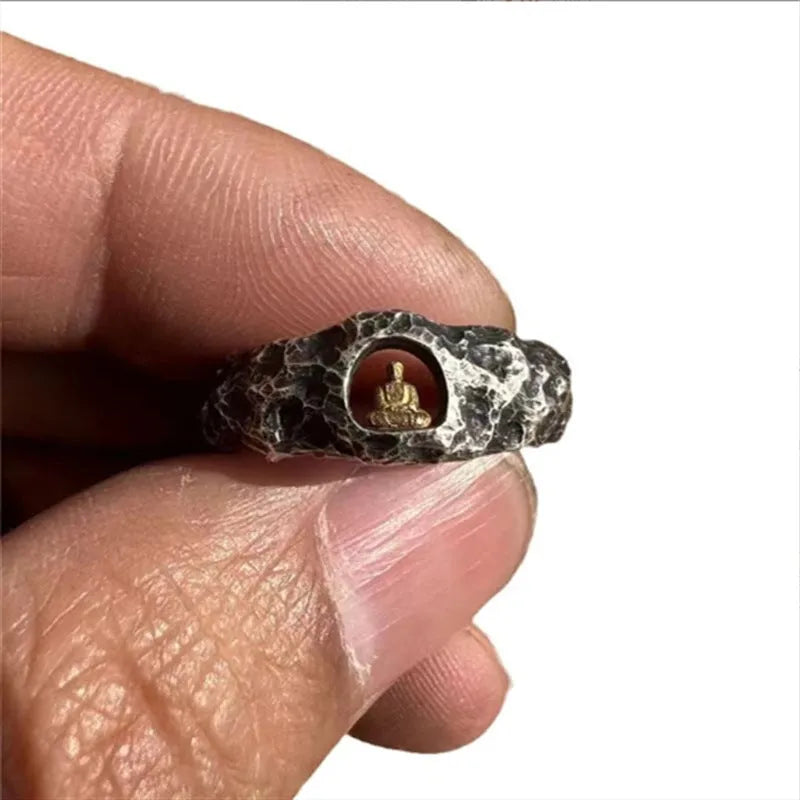 Close-up of a hand-forged copper Grotto Buddha ring with a rough rock texture on a size 8 finger.