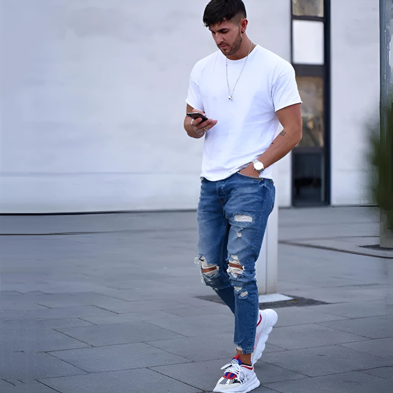 Deep blue men's jeans with distressed holes on the knees, laid flat.