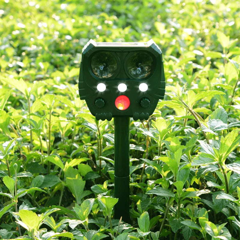 Green solar ultrasonic animal repeller unit with LED strobe lights for outdoor pest control.