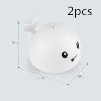 Whale-shaped baby bath toy with automatic water spray and colourful lights floating in water.