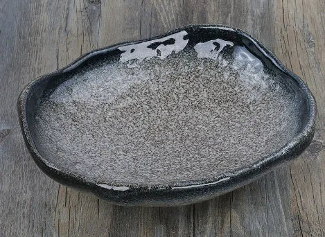 Creative Japanese ceramic sashimi bowl with irregular shape and floral decoration on table