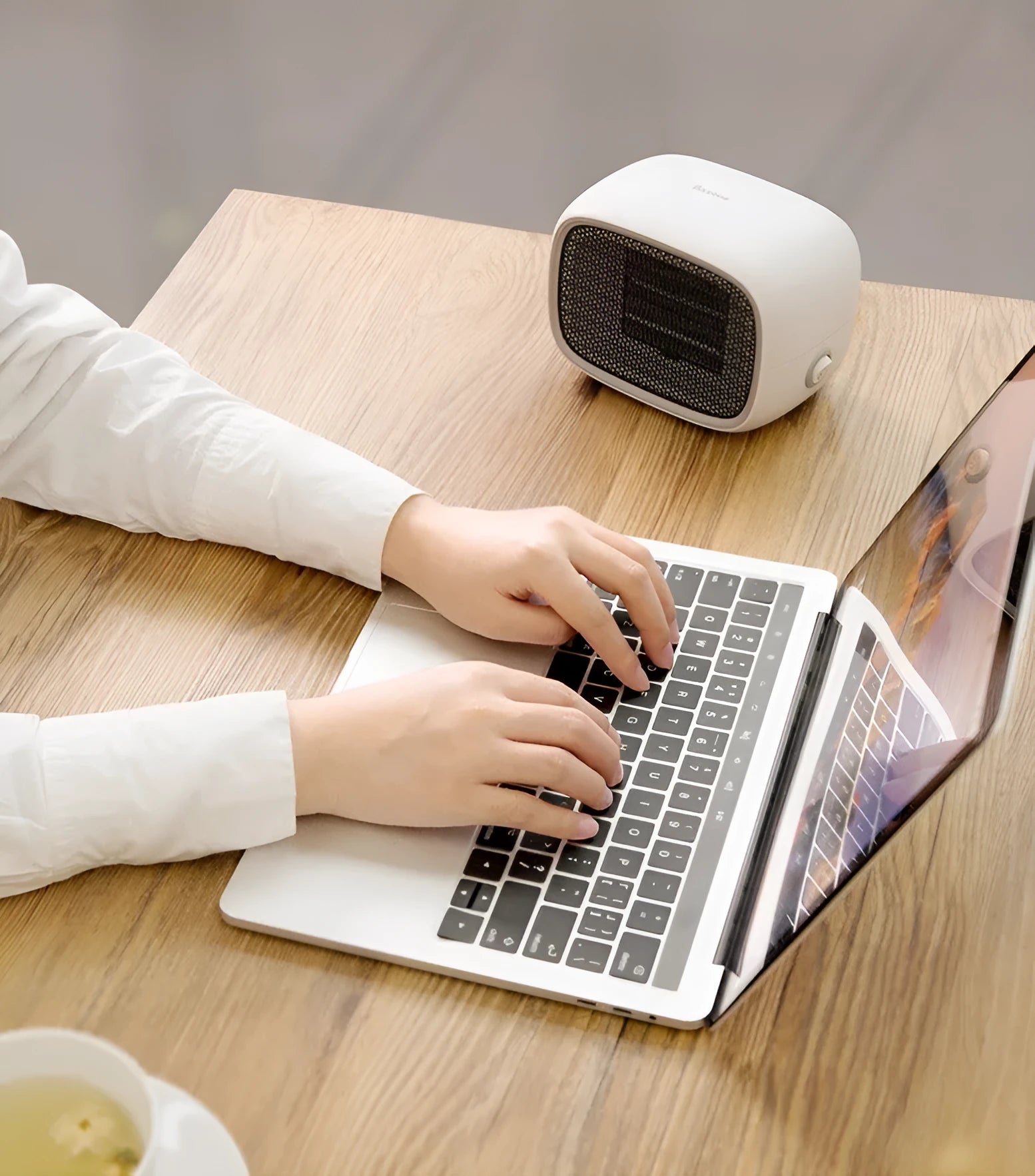 Compact green mini ceramic desk heater with metal mesh front grille, shown next to a pen for scale.