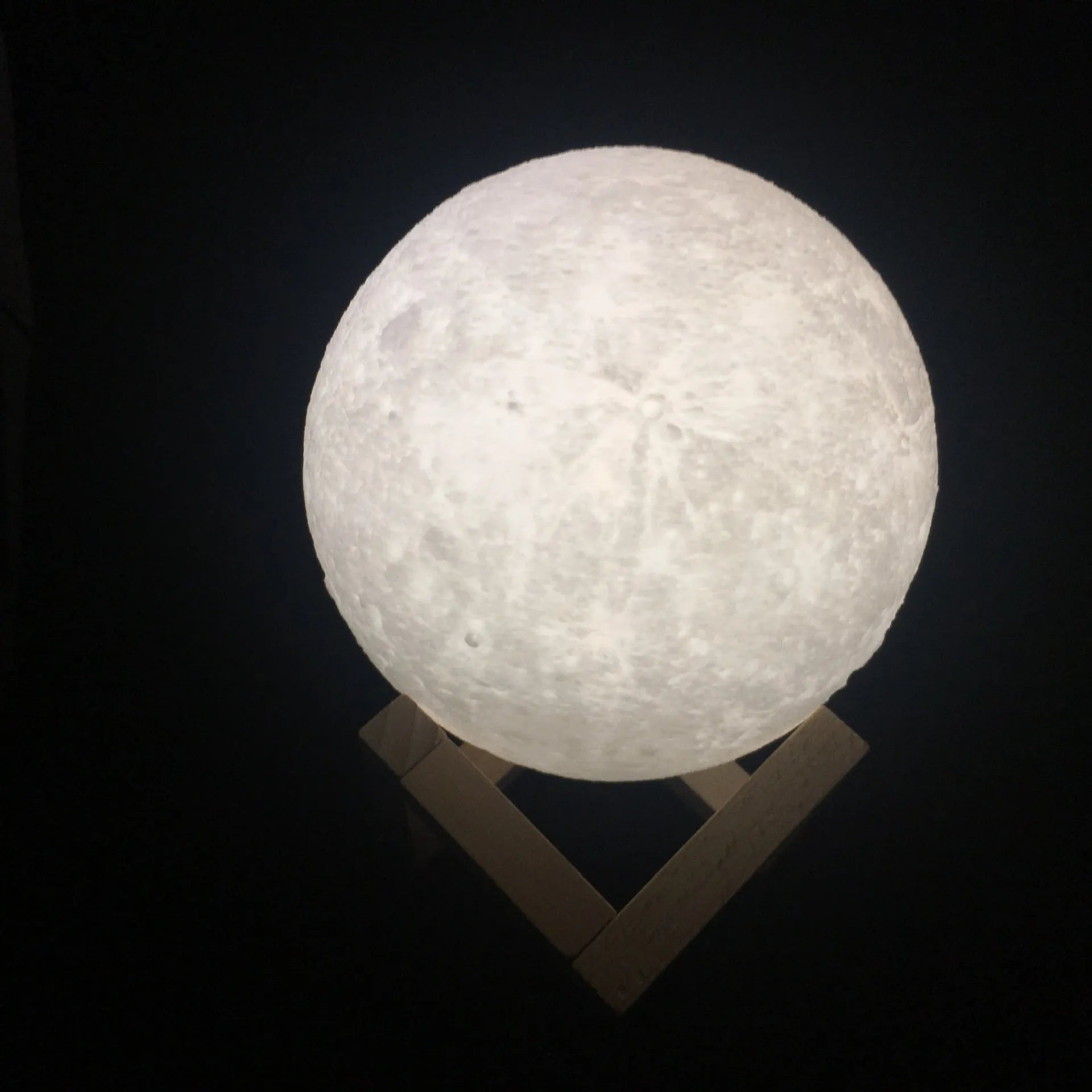 3D printed white moon lamp on wooden stand showing detailed lunar surface texture.