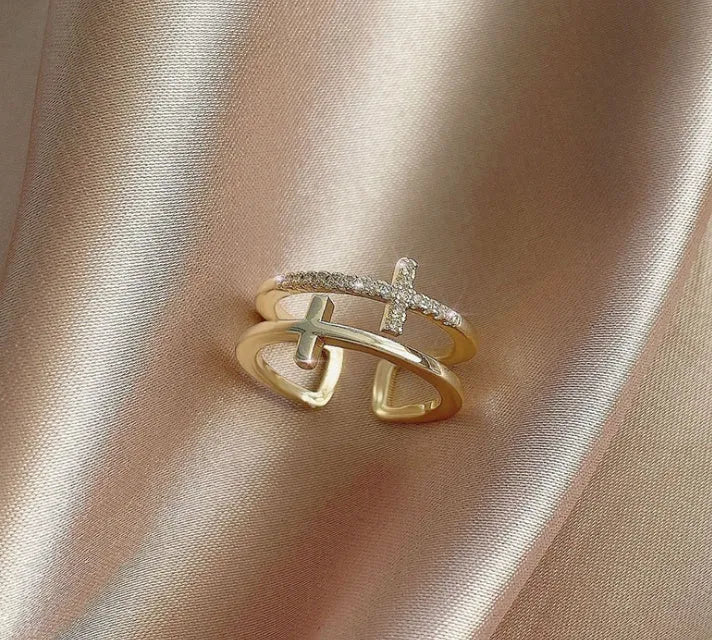 Adjustable open copper ring with geometric double cross design and inlaid zircon stones in gold colour finish.