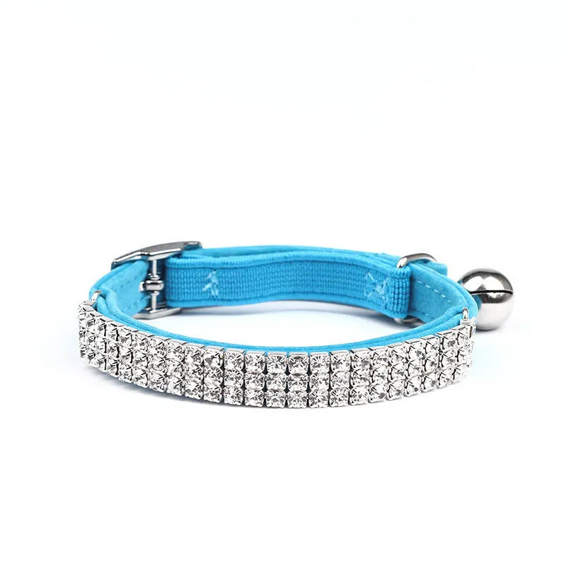 A soft red velvet cat collar with a line of rhinestones, showing the adjustable buckle.