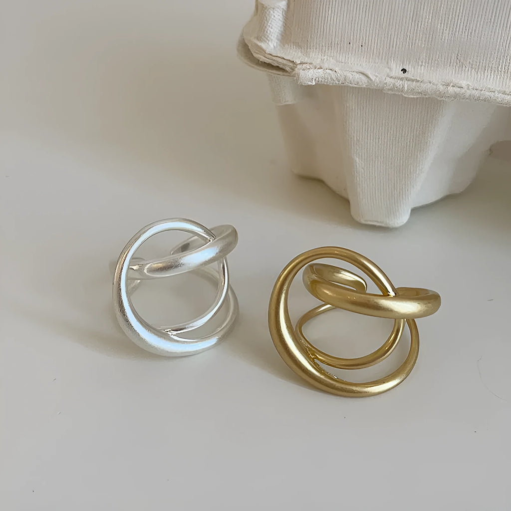 Geometric open ring for women with 3D interlaced matte metal design, shown in gold plating.