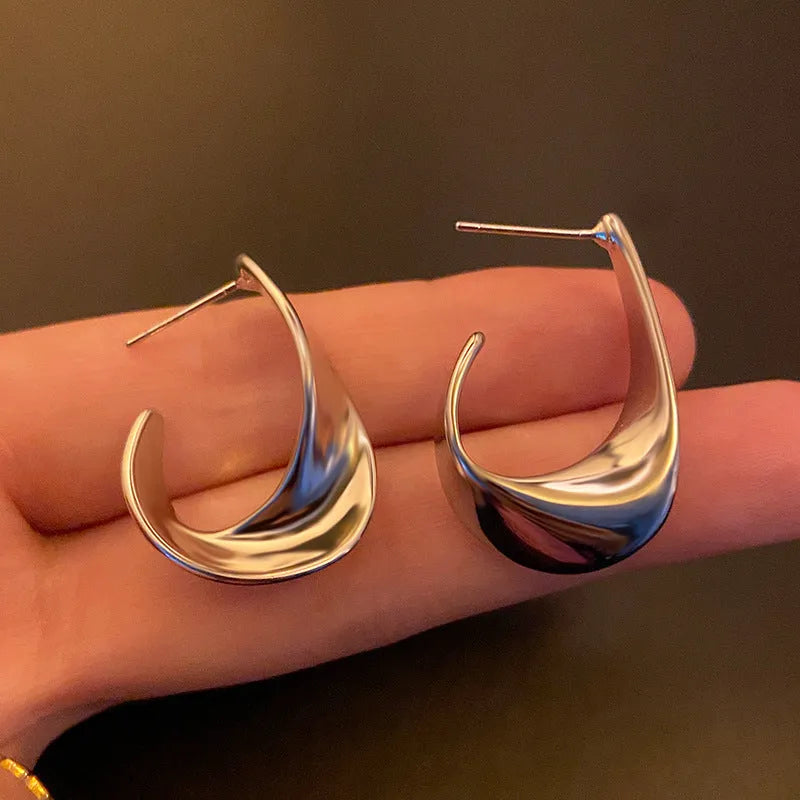 A pair of geometric round earrings with a twisted metal design in a gold electroplated finish.
