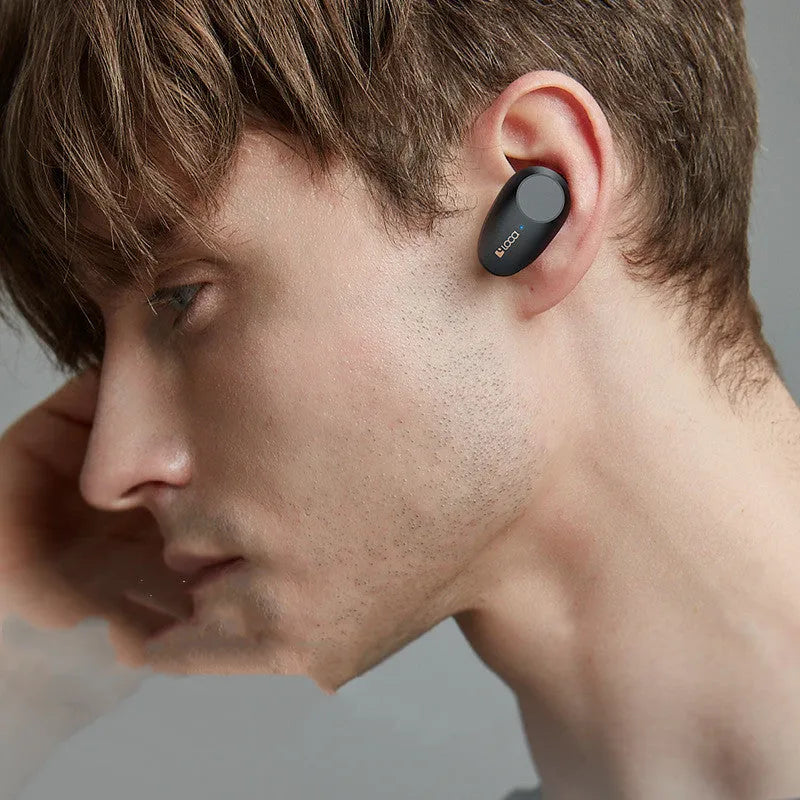 Black wireless Bluetooth headphones with charging case on a table.