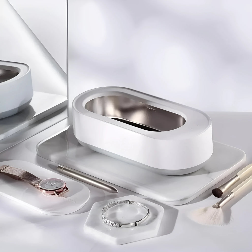 White portable ultrasonic cleaner with stainless steel tank and a single control button.