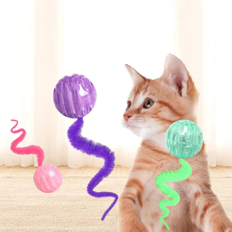 Green bouncy ball cat toy with plush tail on wooden floor