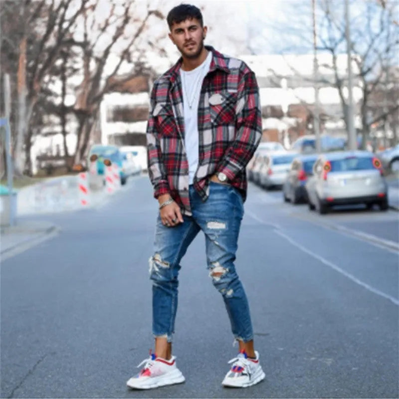 Deep blue men's jeans with distressed holes on the knees, laid flat.