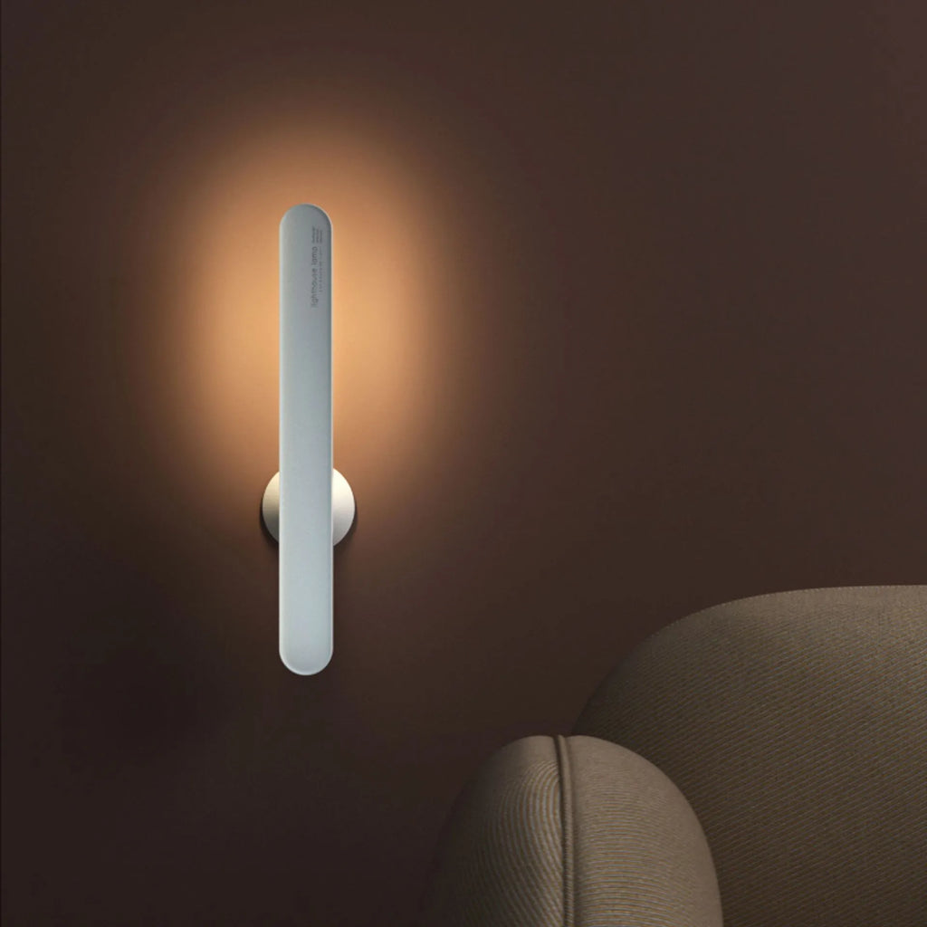 White geometric desk lamp with touch control and magnetic base on a wooden table.