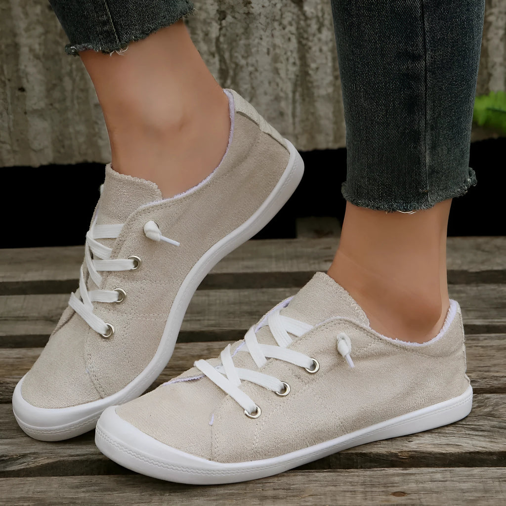 Creamy white low-top women's casual sneakers with a fabric upper and rubber sole.