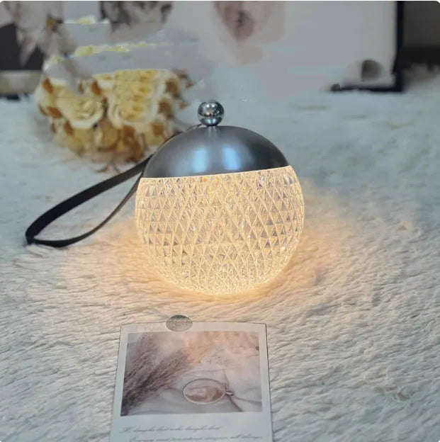 Small portable dimmable night lamp in chrome finish on wooden bedside table