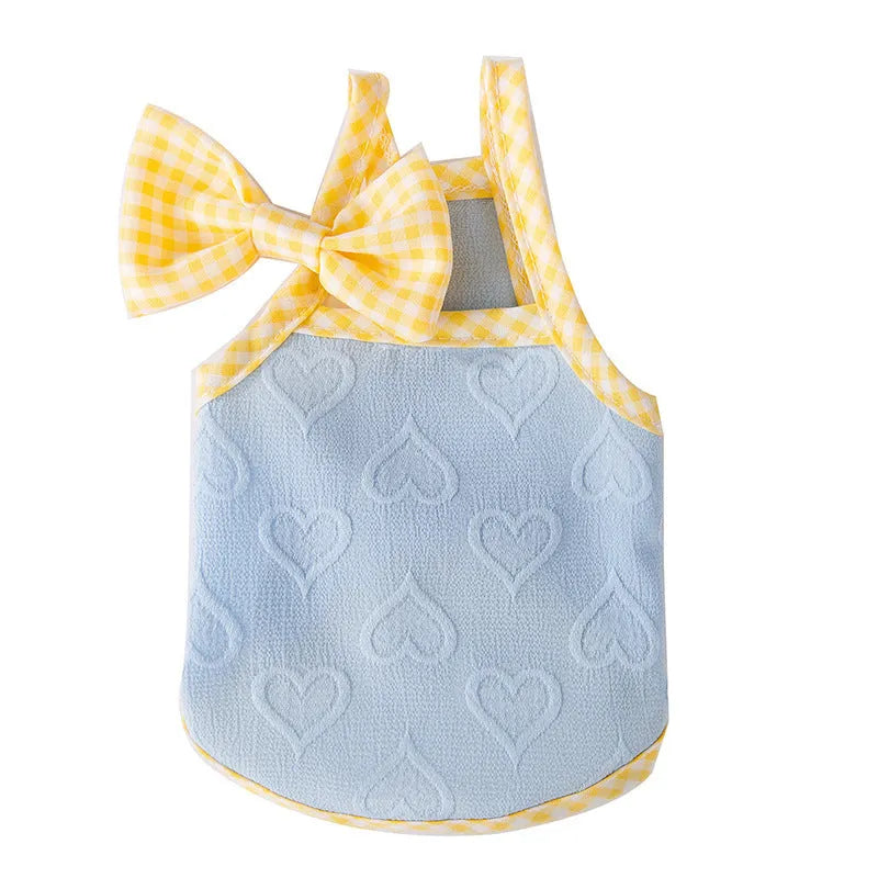 Small dog wearing a blue heart-texture vest with bow suspenders and a matching hairband.