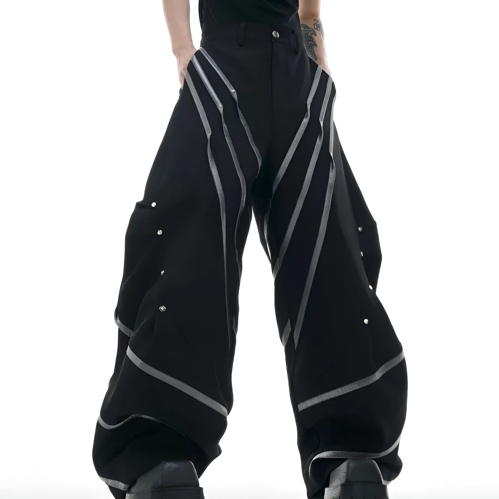 Men's black trousers with white pleated detail and silver metal striped rivets, showing the three-dimensional cut.