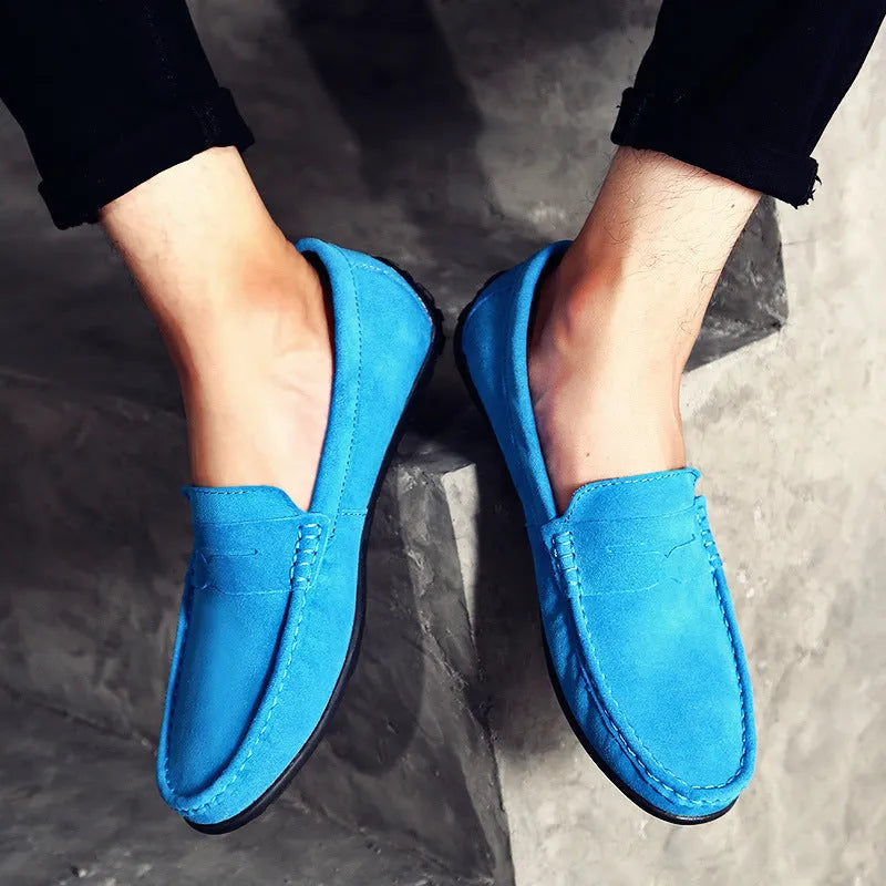 Men's suede leather Gommino loafers in black on a flat rubber sole, showing round toe and sewing line detail.