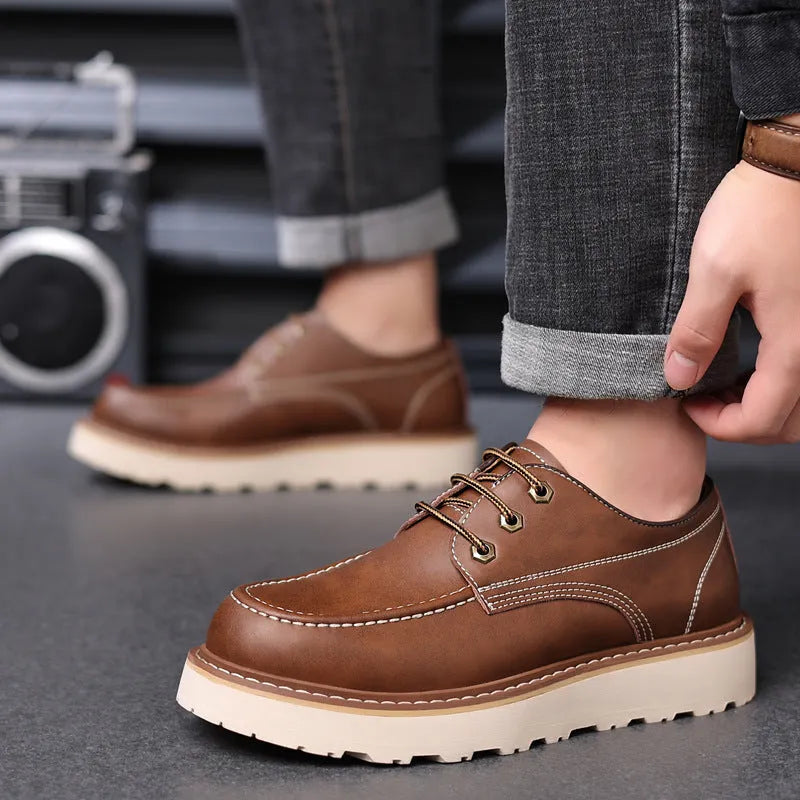 Men's black low-top Martin boots with a round toe and non-slip rubber sole on a plain background.