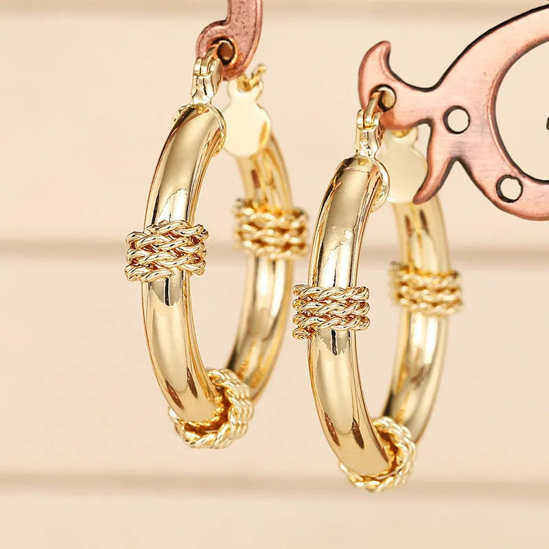 Pair of golden geometric copper earrings with ring and line design details.