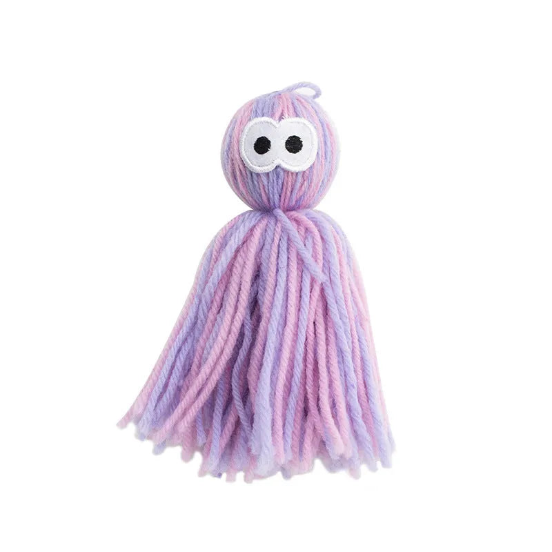 Blue grey hanging wool ball cat toy and teaser stick on a plain background.