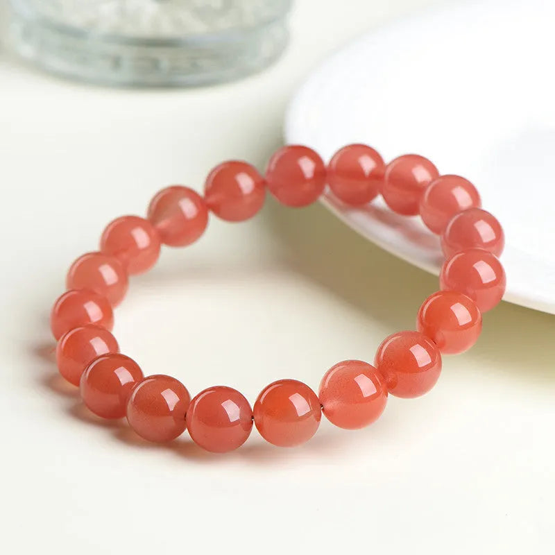 Natural South cherry red agate bracelet showing polished stone beads in scattered arrangement
