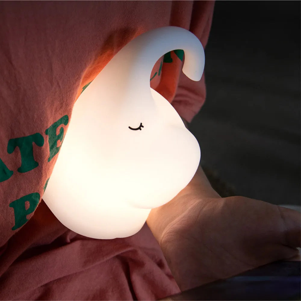 DOMI elephant-shaped silicone night light with warm white glow on a bedside table.