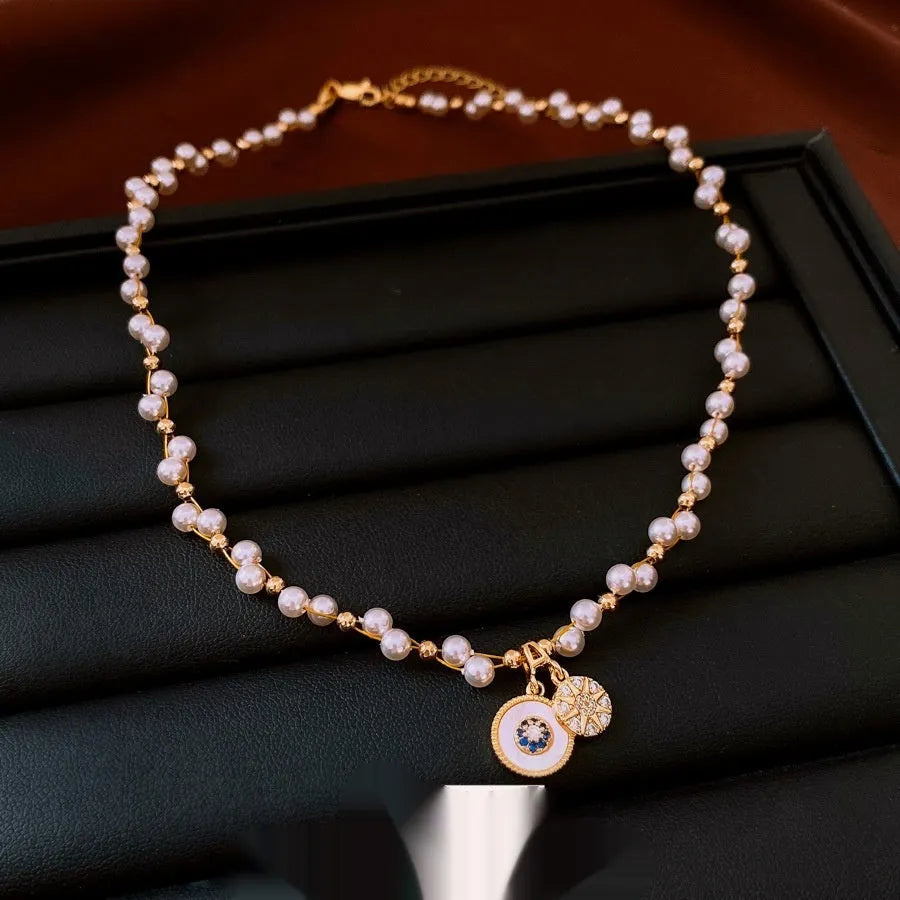 Gold electroplated necklace with round imitation pearl pendant and zircon detailing on adjustable clavicle chain